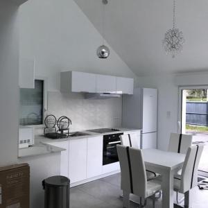 a kitchen with white cabinets and a table and chairs at Studio indépendant 35M2, avec grand jardin, gare 5 min, parkings, wifi THD, prox plage in Vannes