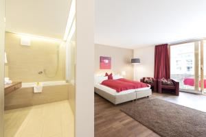 a bedroom with a red bed and a bathroom at Skihotel Galzig in Sankt Anton am Arlberg