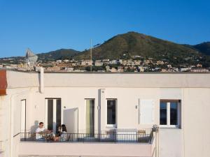 people on a balcony with a mountain in the background at Sea Luxury Suites in Cefalù
