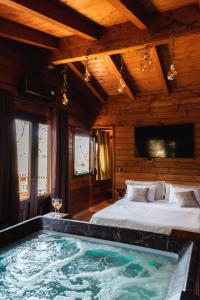Mini spa in chalet bosco في تْشيستيرنِنو: غرفة نوم مع سرير وحوض استحمام كبير
