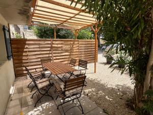eine Terrasse mit einem Tisch und Stühlen unter einer hölzernen Pergola in der Unterkunft Le Mas de la Vinçane in Pernes-les-Fontaines
