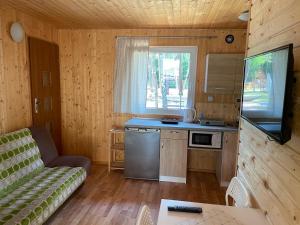 Una sala de estar con un sofá y una cocina. en Domki Letniskowe Korona, en Pogorzelica