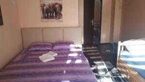 a bed with purple sheets in a small room at Apartman Dunja Banja Vrdnik in Vrdnik