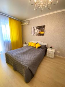 ein Schlafzimmer mit einem Bett mit gelben Kissen und einem Kronleuchter in der Unterkunft MEDINAHOTELKZ, # 63, вид на горы, 15 мин пешком до арбата, HALAL in Almaty