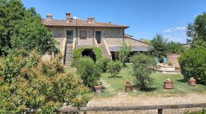 an old house with a yard with trees and plants at Casale Refoli in Casole dʼElsa