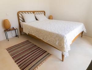 1 dormitorio con 1 cama con manta blanca y alfombra en Villa Louloudia stylish luxury villa with private pool, en Pitsidia