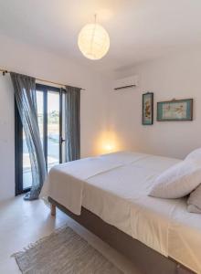 Un dormitorio con una cama grande y una ventana grande. en Villa Louloudia stylish luxury villa with private pool, en Pitsidia