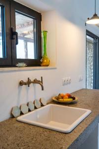 a kitchen counter with a sink and a bowl of fruit at Villa Louloudia stylish luxury villa with private pool in Pitsidia