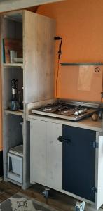 a kitchen with a stove and an open cabinet at Safaritent Lodge 5 in Ruurlo