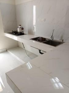 a white kitchen with a sink and a counter at Guest House Gani Syariah in Paret