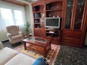 ein Wohnzimmer mit einem TV und einem Couchtisch in der Unterkunft Apartamento A Tenencia in Sada