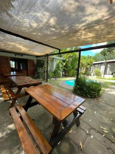 zwei hölzerne Picknicktische unter einem Dach auf einer Terrasse in der Unterkunft Occi Lodge in Sodwana Bay