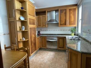 una cucina con armadi in legno e lavandino di Apartamento A Tenencia a Sada