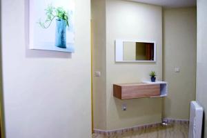 een badkamer met een spiegel en een vaas met een plant erin bij Alojamiento turístico San Vicente in Baeza