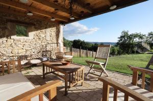 un patio con mesas y sillas de madera y un edificio de piedra. en Aporia en Hostun