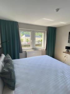 1 dormitorio con 1 cama blanca grande con cortinas verdes en Hotel LA PLAGE en Bouillon