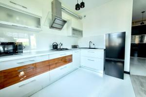 a kitchen with white cabinets and a black refrigerator at Apartament Ogrodowy Zakątek in Uniejow