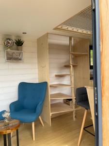 a room with a blue chair and a book shelf at Tiny house avec spa privatif 