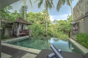 a swimming pool in front of a house with trees at Griya Shanti Villas & Spa in Ubud