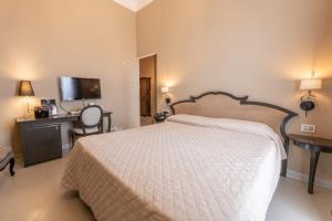 a bedroom with a bed and a desk and a television at Villa Mosca Charming House in Alghero