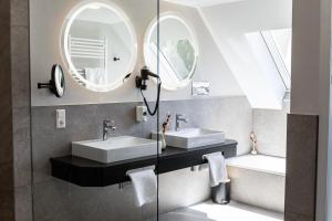 a bathroom with two sinks and two mirrors at Landhaus Lauble in Hornberg +139 photos