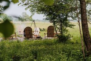 a couple of chairs and a swing in a field at Dziki Las - domki na drzewach in Miłomłyn