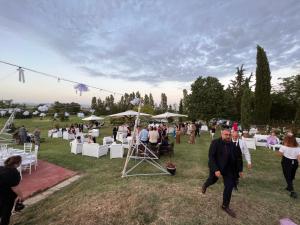 un grupo de personas caminando por un campo con mesas y sillas en Casa Burraia, en Abbadia di Montepulciano