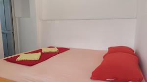 a bed with two red pillows and a red blanket at Guest's house ''Lindi&Roni'' in Ulcinj