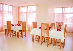 a dining room with two tables and chairs and windows at Ambiere House in Mtwara