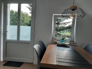 een eetkamer met een houten tafel met stoelen en ramen bij Ferienwohnung Muh - Ostfriesland nähe Nordsee in Rechtsupweg