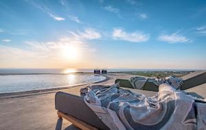 een bed zittend op het strand met de zonsondergang bij Saint Apostles Villas in Fira