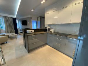 a kitchen with white cabinets and a living room at LA PERLA in Pobierowo