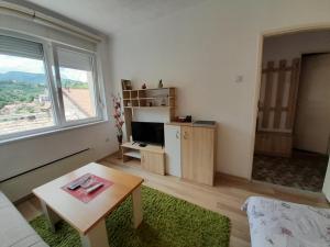 a living room with a large window and a table at Apartman Trg Višegrad in Višegrad