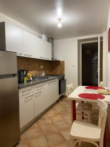 a kitchen with white cabinets and a table and a refrigerator at Appartement Rez de chaussée T2 centre-ville in Vendôme