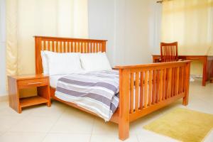um quarto com uma cama com uma estrutura de madeira e uma mesa de cabeceira em Ambiere House em Mtwara