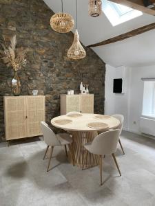 a table and chairs in a room with a stone wall at Au temps suspendu in Marche-en-Famenne