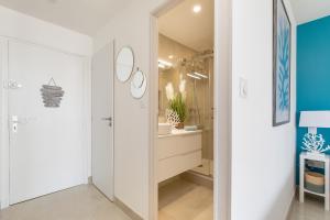 een witte badkamer met een wastafel en een spiegel bij Blue Coral Heliopolis Naturiste in Cap d'Agde