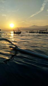 um pôr do sol na praia com barcos na água em Barclona Guesthouses Lovina em Pabean Buleleng