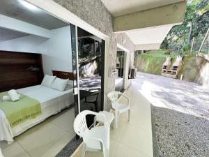 邦比尼亞斯的住宿－Refúgio da Lagoinha - Centro de Bombinhas，一间卧室配有一张床和两把椅子,并设有一个阳台
