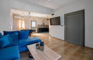Loulaki villas santorini في Vourvoúlos: غرفة معيشة مع أريكة زرقاء وطاولة