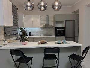 a kitchen with a white counter and black chairs at SEA HORIZON SUITES in Chalkida +5 photos