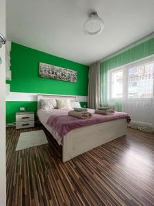 1 dormitorio con paredes verdes y 1 cama grande en Best Apartament Calan, en Călan