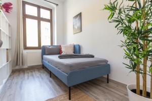 a blue chair in a living room with a plant at FullHouse - Chemnitz - Z25 Apartments - 3 Beds - SmartTV - Nespresso in Chemnitz