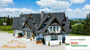 a house with a black roof on top of it at Miodowy Dworek in Bukowina Tatrzańska