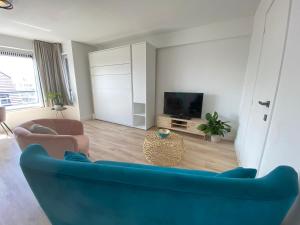ein Wohnzimmer mit einem blauen Sofa und einem TV in der Unterkunft Happy stay by Anaïs - 20m to beach in De Panne