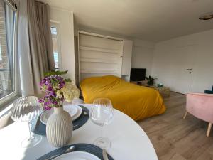 ein Wohnzimmer mit einem Bett und einem Tisch mit Weingläsern in der Unterkunft Happy stay by Anaïs - 20m to beach in De Panne