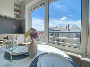 a dining room table with a vase of flowers and a window at Happy stay by Anaïs - 20m to beach in De Panne