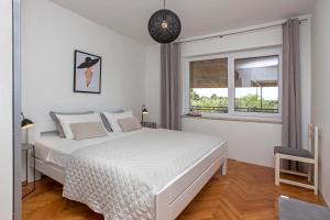 Un dormitorio blanco con una cama y una ventana. en "Andrija" apartmen's, en Banjole