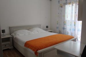 a bedroom with a bed with an orange blanket on it at Jovan Vukovic in Kotor