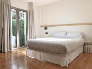 a white bedroom with a bed and a large window at Hotel As Hortensias in Corcubión